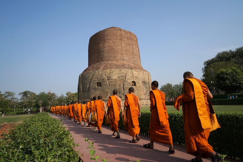 Buddhist monks walking candlelit Or publish dharma at Dhamek Stupa at Sarnath near Varanasi or Madhya Pradesh India, the concept of travel incredible India.
